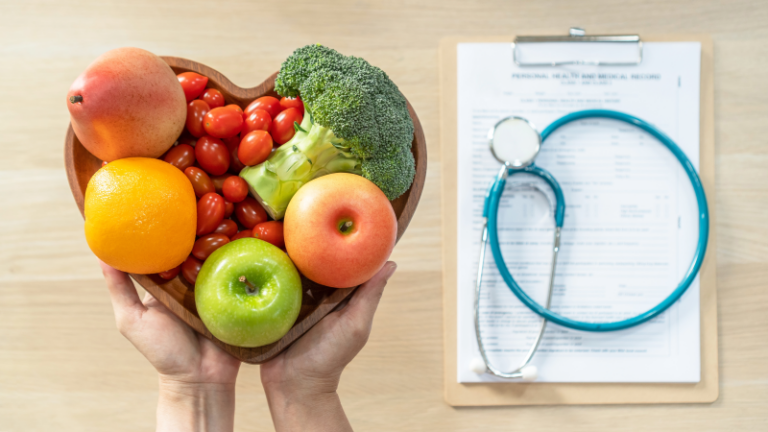 heart bowl with fruits and veggies with medical paperwork.